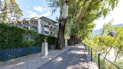 a tree lined street with a building in the background at Flora Hotel & Suites in Merano