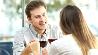 a man and woman sitting at a table with a glass of wine at Flora Hotel & Suites in Merano