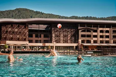 a group of people playing with a beach ball in a swimming pool at Falkensteiner Family Resort Lido l 4 Star Superior in Chienes