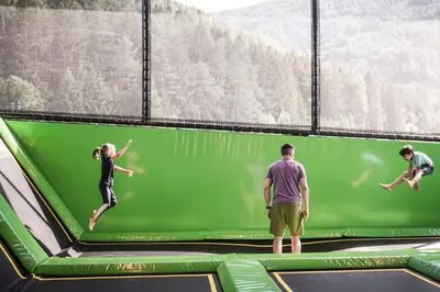 a group of three people jumping on an indoor trampoline at Falkensteiner Family Resort Lido l 4 Star Superior in Chienes