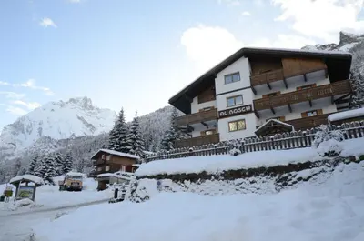 a building with snow on the ground in front of it at Cèsa Al Bosch in Alba di Canazei
