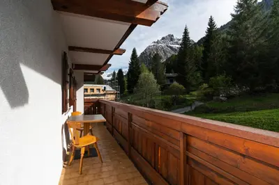 a balcony with a table and chairs and a mountain at Cèsa Al Bosch in Alba di Canazei