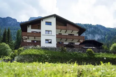 a building on a hill with mountains in the background at Cèsa Al Bosch in Alba di Canazei