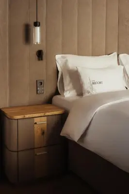 a bed with white pillows and a night stand at Hotel Recort - Adults Only in Colfosco