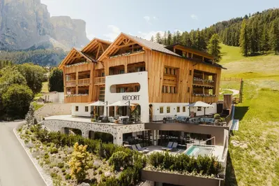 an apartment building with a pool in front of a mountain at Hotel Recort - Adults Only in Colfosco