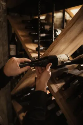 a person holding a bottle of wine in a wine cellar at Hotel Recort - Adults Only in Colfosco