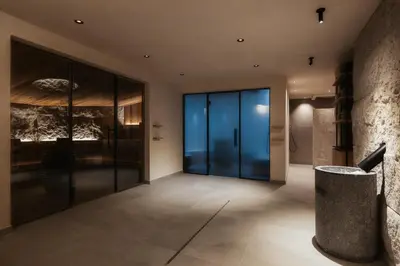 a hallway with glass doors and a stone wall at Hotel Recort - Adults Only in Colfosco