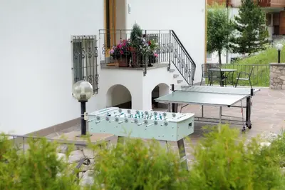 a ping pong table on a patio with a table at Apartments La Mana in Santa Cristina in Val Gardena