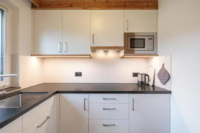 a kitchen with white cabinets and a microwave at Apartments La Mana in Santa Cristina in Val Gardena
