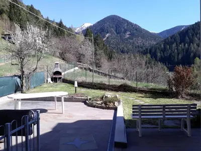 a park with two benches and a view of a mountain at La cà di nonna Natalia in Brusago