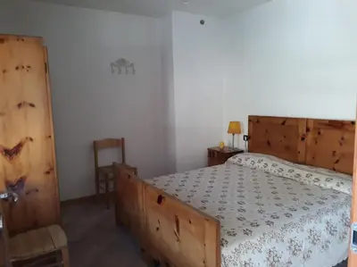 a bedroom with a large wooden bed and a chair at La cà di nonna Natalia in Brusago