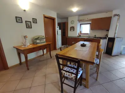 a kitchen with a wooden table and a dining room at La cà di nonna Natalia in Brusago