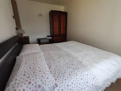 a bed with a white bedspread with pink flowers on it at La cà di nonna Natalia in Brusago
