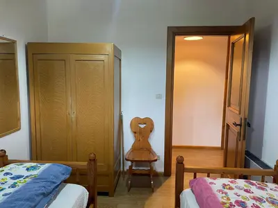 a bedroom with a bed and a chair next to a door at Mansarda Mulaz in Falcade