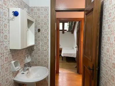 a bathroom with a sink and a mirror and a hallway at Mansarda Mulaz in Falcade