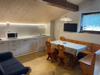 a kitchen and dining room with a table and chairs at Mansarda Mulaz in Falcade