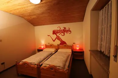 two beds in a room with a dragon on the wall at Residence Ben Ste in Ortisei
