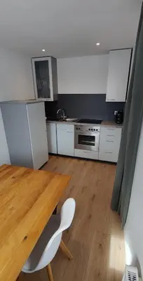 a kitchen with a wooden table and white cabinets at Alp-Hof Apartments in Stanghe