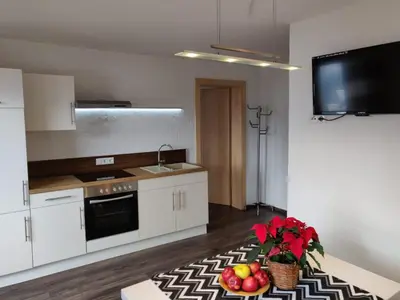 a kitchen with white cabinets and a table with fruit on it at Alp-Hof Apartments in Stanghe