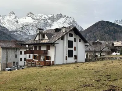 a house in a field with mountains in the background at Sole e Neve -Sun & Snow in Forno di Zoldo