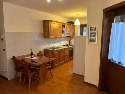 a kitchen with a wooden table and a refrigerator at Sole e Neve -Sun & Snow in Forno di Zoldo