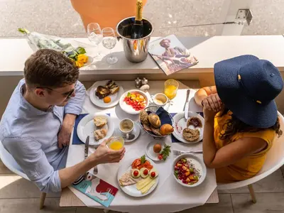 a man and a woman sitting at a table with food at SCHLOSSHOF SÜDTIROL - Hotel & Camping Resort in Lana