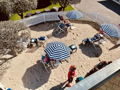 a group of people sitting in chairs under umbrellas in the sand at SCHLOSSHOF SÜDTIROL - Hotel & Camping Resort in Lana