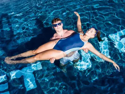 a man and woman laying in a swimming pool at SCHLOSSHOF SÜDTIROL - Hotel & Camping Resort in Lana