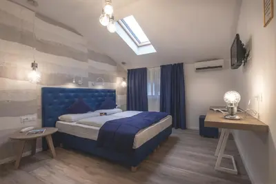 a bedroom with a blue bed and a television at SCHLOSSHOF SÜDTIROL - Hotel & Camping Resort in Lana