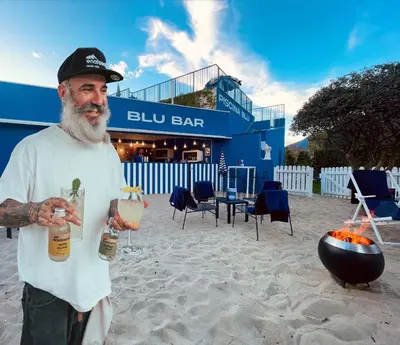 a man standing on the beach holding a drink at SCHLOSSHOF SÜDTIROL - Hotel & Camping Resort in Lana