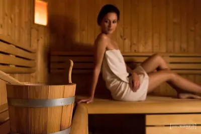 a woman is sitting in a sauna at Alping Apartments in Brunico