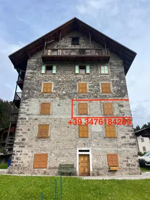 a large stone building with wooden doors and windows at Stella Alpina - Romantic getaway in Falcade