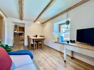 a living room with a table and a television at Stella Alpina - Romantic getaway in Falcade