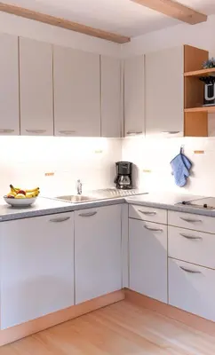 a kitchen with white cabinets and a sink at Apartment Getzenbergerhof in Chienes