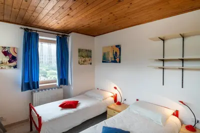 two beds in a bedroom with blue curtains at Casa Rosina in Tesero