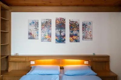 two beds in a room with paintings on the wall at Casa Rosina in Tesero