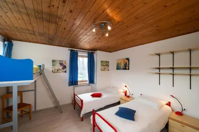 a bedroom with two beds and a wooden ceiling at Casa Rosina in Tesero