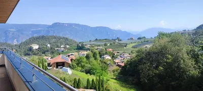 a small village on a hill with mountains in the background at Janas Bolzano Mountain Apartment in Tesimo