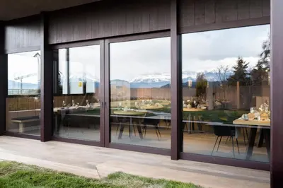 a glass house with a dining room with a view of the mountains at Served Apartements Belvedere in San Genesio Atesino