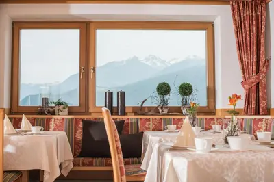a restaurant with tables and a view of mountains at Hotel Garni Hochgruber in Brunico