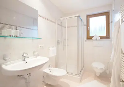 a bathroom with a sink and a toilet and a shower at Hotel Garni Hochgruber in Brunico