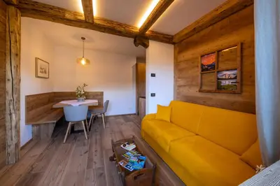 a living room with a yellow couch and a table at Cesa dele Angele in Colle Santa Lucia