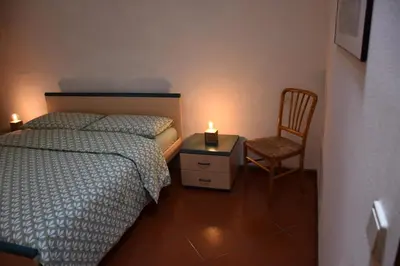 a bedroom with a bed and a chair with a candle at Appartamento Aquila D'oro in Vipiteno