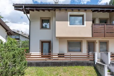 a house with a wooden bench in front of it at Bilo Cornetto Bianco in Predazzo