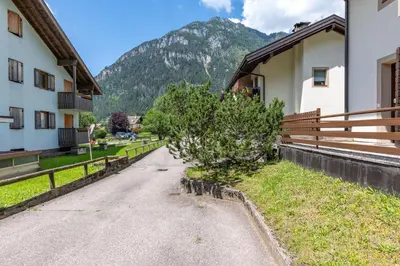 a road between two buildings with a mountain in the background at Bilo Cornetto Bianco in Predazzo