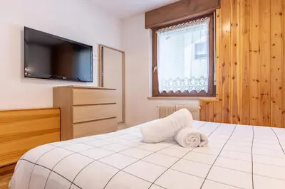 a bedroom with a bed and a flat screen tv at Bilo Cornetto Bianco in Predazzo