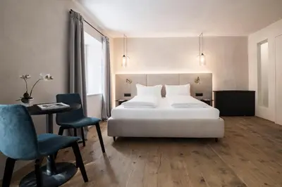 a bedroom with a white bed and a table and chairs at Alte Schmiede Apartments & Rooms in Bolzano