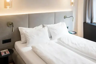 a bed with white sheets and pillows in a room at Alte Schmiede Apartments & Rooms in Bolzano