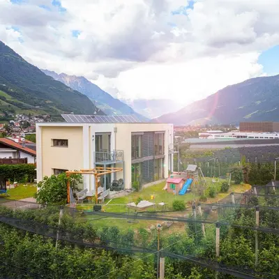 a house on a hill with mountains in the background at Biohof Gala in Naturno