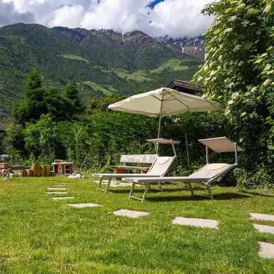 two lounge chairs and an umbrella in the grass at Biohof Gala in Naturno